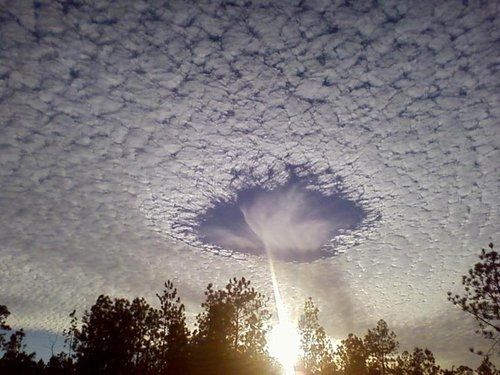 lanciare: This is a rare meteorological phenomenon called a skypunch. When people see these, they think it’s the end of the world. Ice crystals form above the high-altitude cirro-cumulo-stratus clouds, then fall downward, punching a hole in the cloud cover. SKYPUNCH