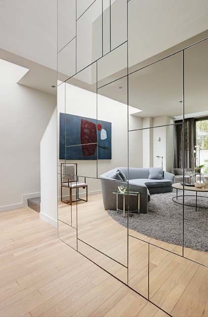 A geometric mirrored wall conceals closets and storage spaces, which are located behind the touch latch mirrored doors. - Serene Notting Hill Studio House Designed by Michael Reeves