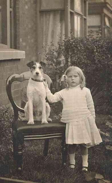 A little girl with her Jack Russell Terrier. Look how proud he is sitting on the chair