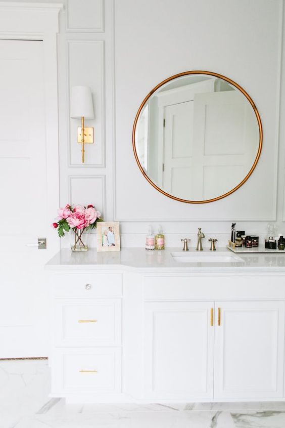 Brass mirror in a white bathroom