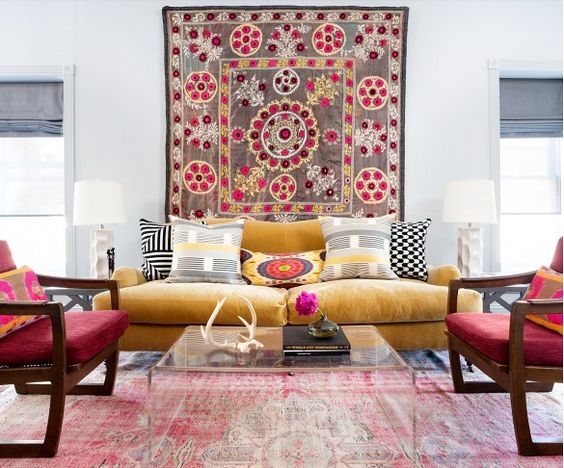 Bright living room with yellow velvet sofa, faded rug, acrylic coffee table, and wall-hung textile