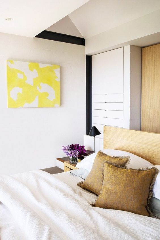 Comfy bedroom with bright yellow art, and a neutral color palette