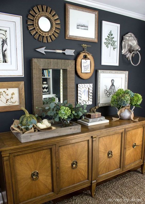 Eclectic gallery wall on dark charcoal walls | console decorated with pumpkins and fall flowers