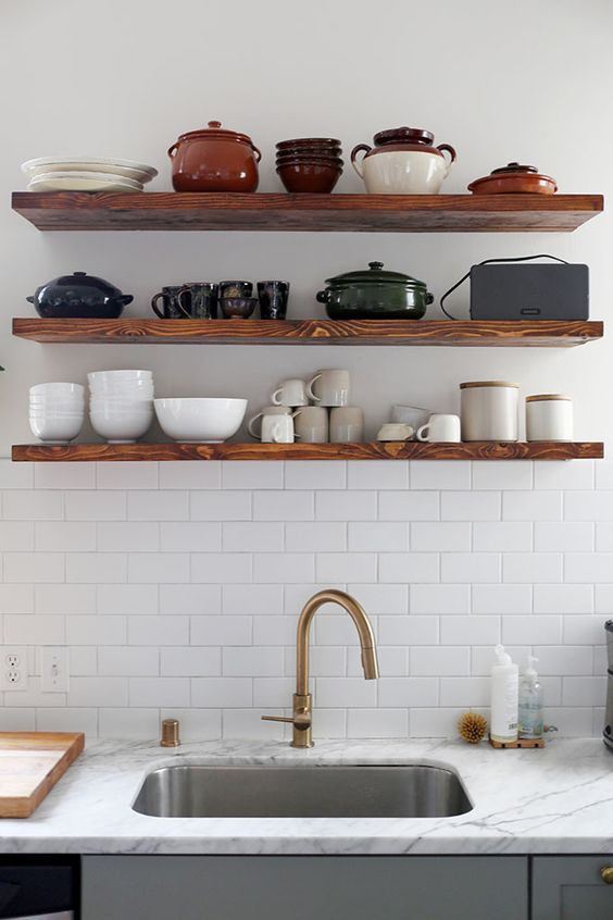 floating wood shelves with white subway tile and brass fixtures