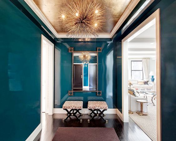 Gold foil wallpaper on the ceiling of this modern entryway/foyer with abstract light fixture