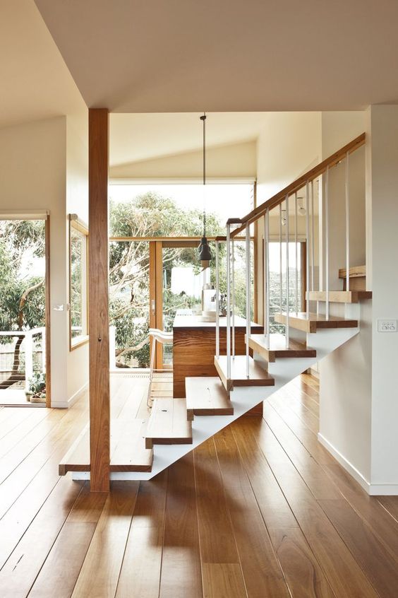 Light wood staircase in airy foyer of window-filled house