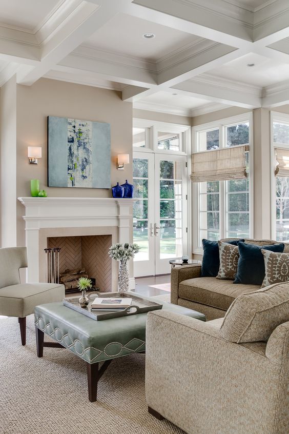 Living room with french doors, coffered ceilings, fireplace with herringbone tile, teal ottoman, beige couched | KL Interiors