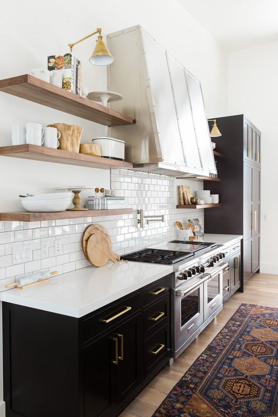 love the ligthing above the open shelves. Statement range hood and black cabinetry. vintage rug in the kitchen. Designed by Studio McGee