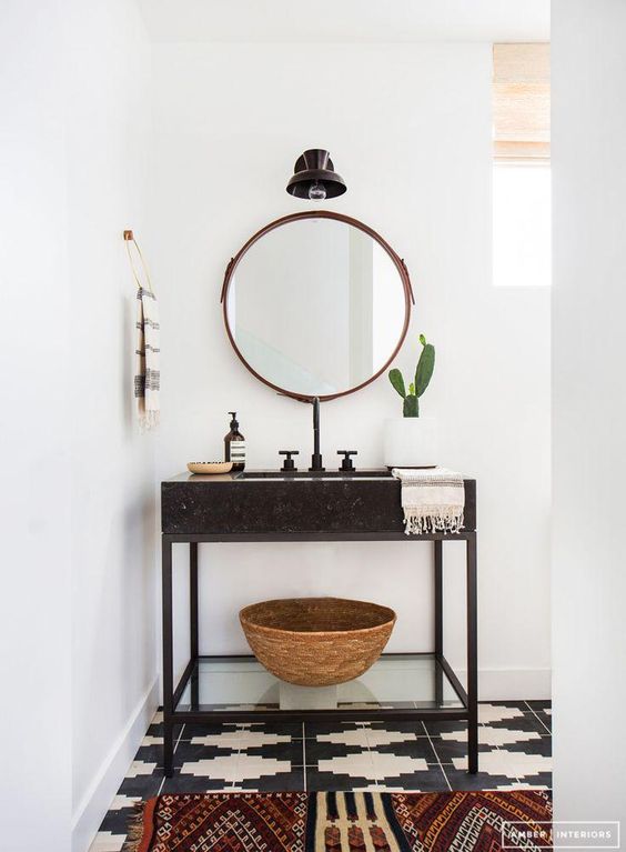 Love this super zen minimalist-meets-boho bathroom with round leather edged mirror and black and white patterned floor tiles.