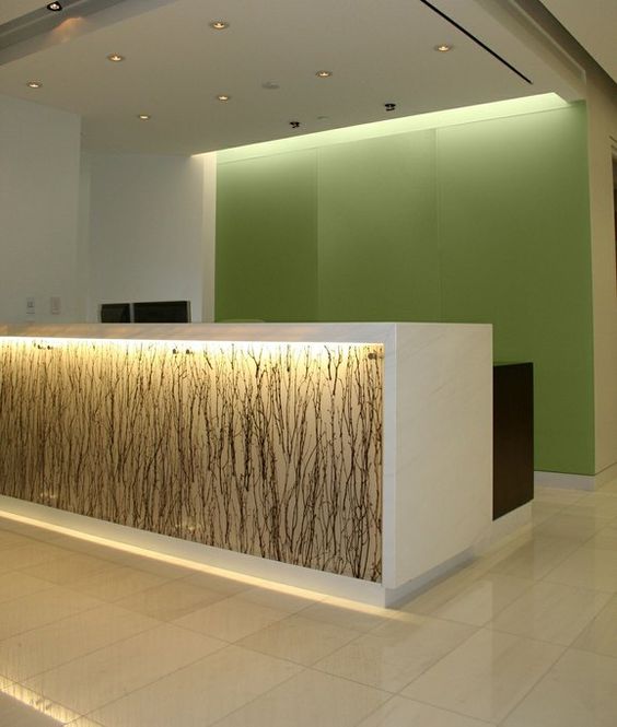 Reception desk with artistic feature, backlit and reflects the effect of the top-lit area behind the desk.