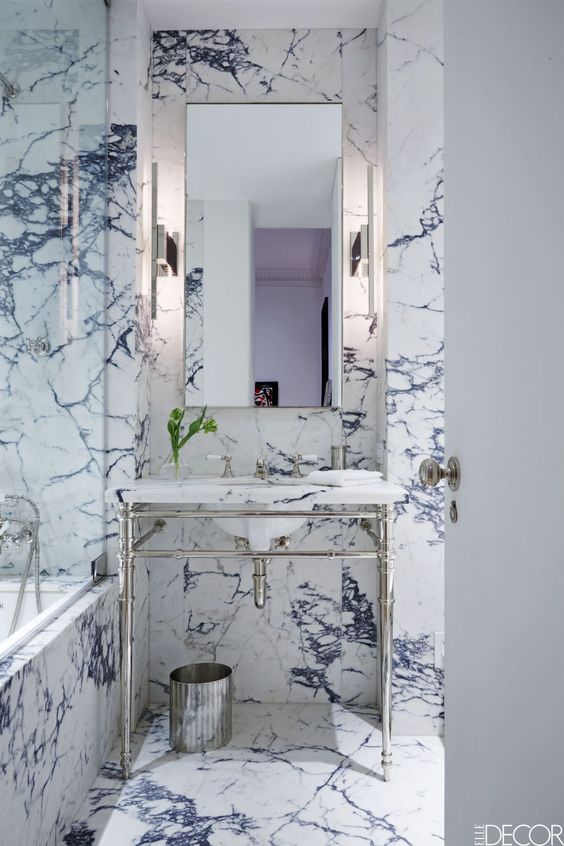 The bathroom vanity and tub are by Waterworks, the fittings are by Lefroy Books, and the sconces are by Ozone; the walls are sheathed in Calacatta Viola marble.