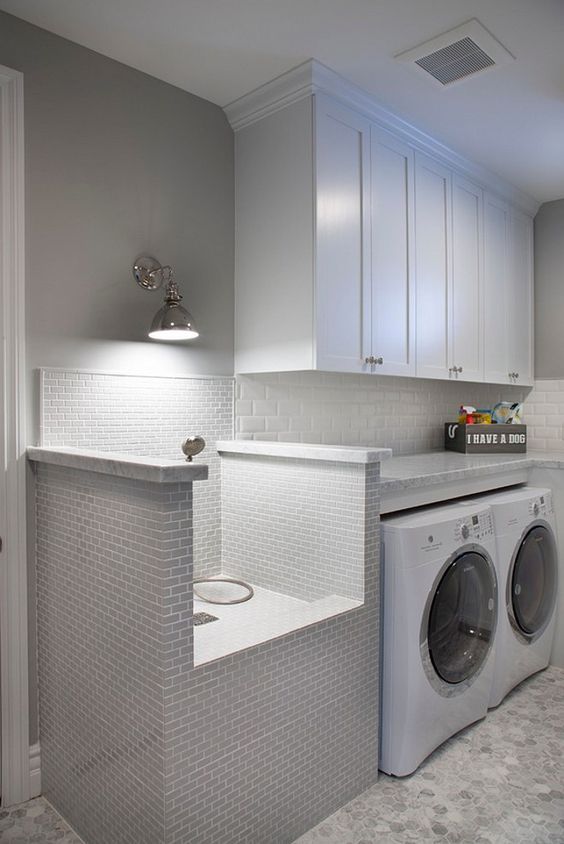 This stunning laundry room features white cabinets and a very practical pet shower and grooming station. Flooring is hex marble tiles.