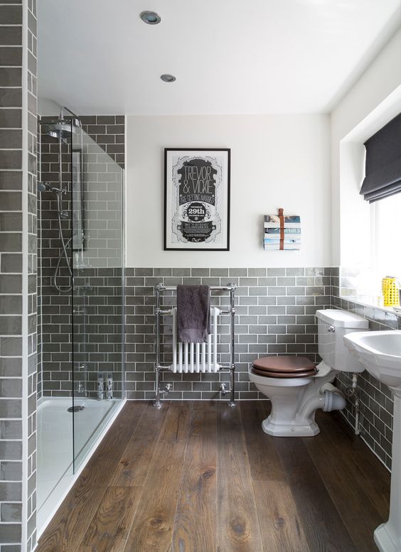 Traditional bathroom with dark rustic wood floors, gray subway tile, glass walk-in shower and white pedestal sink | Interior Therapy