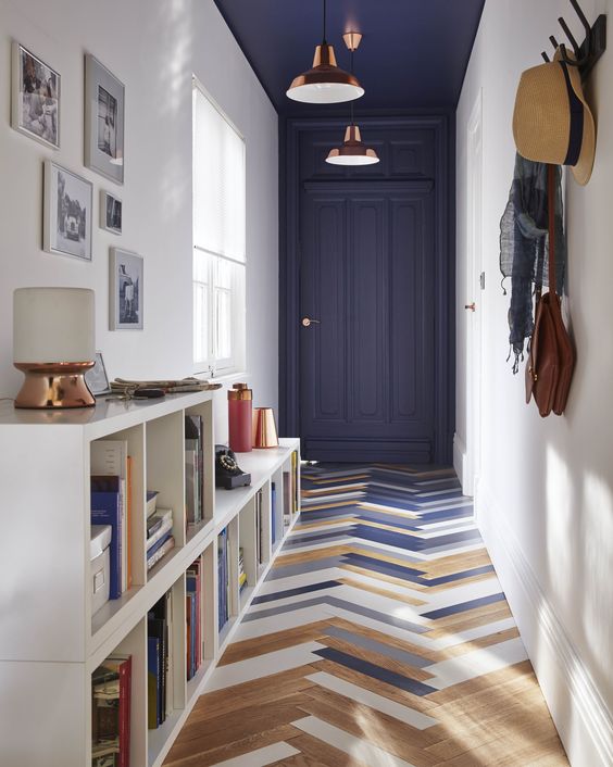 Un joli couloir / entrée, avec son parquet peint en tons de bleu ardoise et de blanc. Le bleu se répand aussi sur le mur du fond et le plafond, créant un intéressant effet de perspective.