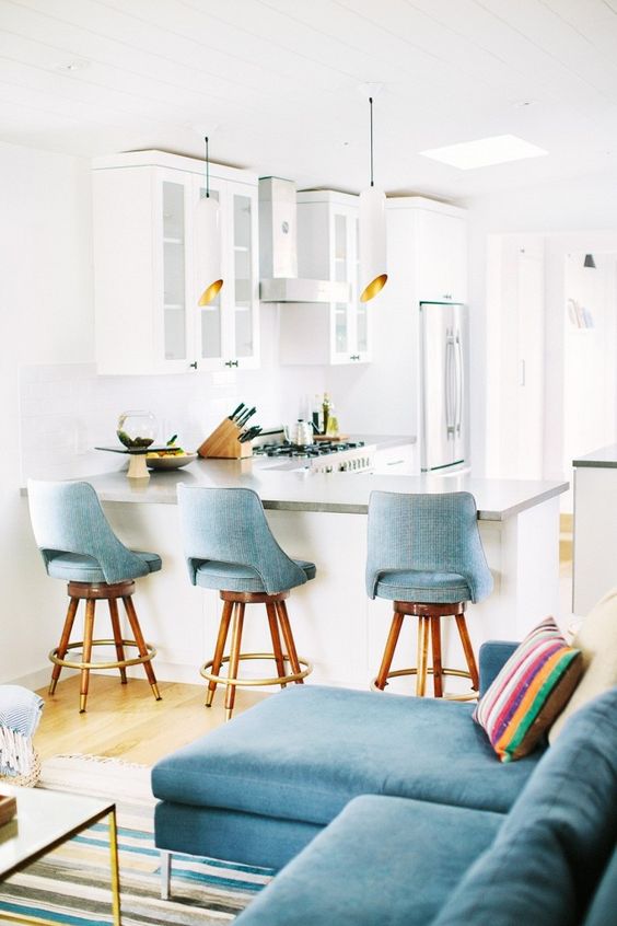 An open bright kitchen with vintage barstools, and pendant lights
