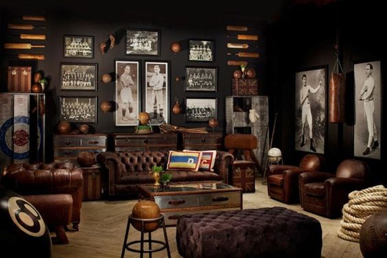 Restoration Hardware sports room/man cave with masculine elements. Brown leather chesterfield sofa, tufted leather ottoman, old world touches, and vintage prints and etchings. I really like the aluminum trunks and club chairs, but I'm not sold on the lockers or the giant 8-ball, which seem a bit gimmicky to me. This room would look even more amazing with a pair of orb chandeliers.