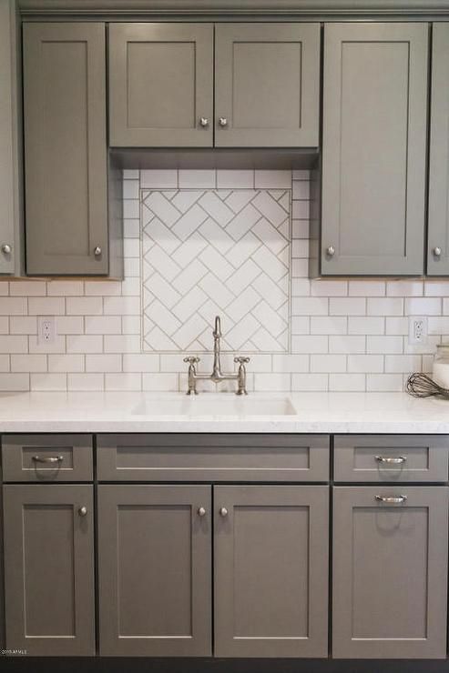 White and gray kitchen features gray shaker cabinets paired with white quartz countertops and a white subway tiled backsplash.