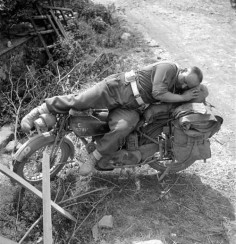 Lance Corporal Bill Baggott sleeps on his motorcycle in Falaise, France - 13 August 1944  Photo by Michael M. Dean