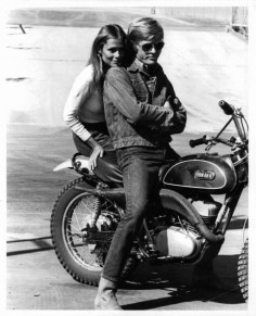 Lauren Hutton sitting on motor bike with Robert Redford