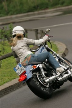 Perfect illustration of the dynamics of turning on a two-wheeled vehicle -- leaning into the turn, so that gravity can balance out the centrifugal force of the turn, and front wheel essentially straight. I also commend the rider for wearing a helmet, and for riding with her arms and legs covered.