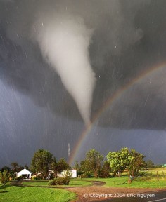 The scene might have been considered serene if it weren't for the tornado. During 2004 in Kansas, storm chaser Eric Nguyen photographed this budding twister in a different light -- the light of a rainbow. Pictured above, a white tornado cloud descends from a dark storm cloud. The Sun, peeking through a clear patch of sky to the left, illuminates some buildings in the foreground. Sunlight reflects off raindrops to form a rainbow. By coincidence, the tornado appears to end right over the rainbow.