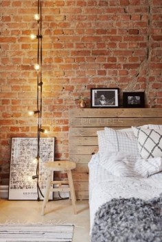 25 gorgeous bedroom decorating ideas - exposed brick walls, wooden headboard, mixed with diamond + grid pattern pillows, a modern wooden stool as a nightstand, string lights +  gray shaggy throw