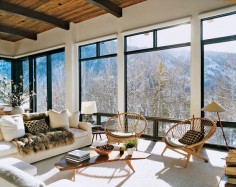 Aerin's Aerie - The light-filled living room features a Jean-Michel Frank sofa, Hans Wegner hoop chairs, luxurious fur throws, and exhilarating views over Aspen Mountain.