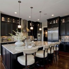 Black cabinets with white countertops and chairs, and a huge kitchen island.