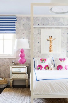 Blue-and-white striped Roman shades and a hot pink bedside bring bright hues to a cheerful girls room.