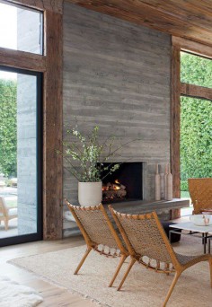 Board-formed concrete fireplace framed by reclaimed-oak beams