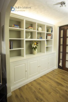 Built in Cabinets and shelving in a large alcove featuring raised panel doors and up lighting. The backing was painted in a darker color to add contrast.