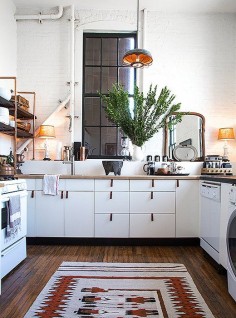 Classic white kitchen cabinets get a rustic update with leather drawer pulls and a vintage Navajo floor runner.