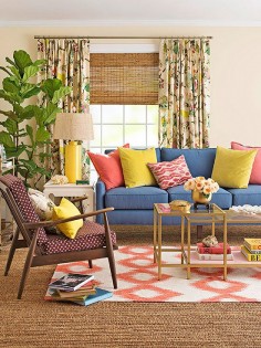 eclectic and colorful living room style | pops of coral, blue, and yellow + layered ikat and natural woven rugs + staked table books + gold accents + fig tree