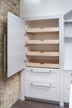 Fabulous kitchen features concealed pantry cabinets fitted with stacked pull out drawers next to an exposed brick wall.