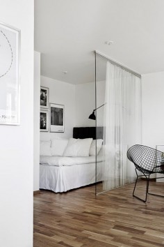 Glass wall and curtains divide the bedroom from the living room. Clever idea for small studios!