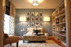 Gorgeous living room design with blue gray walls paint color, tan sofa settee, floral rectangular ottoman, gray table, polished chrome floor lamps, flokati rug, white garden stool, bookcase and black & white photo gallery.