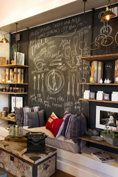 industry-home; chalkboard wall behind shop display. Such a cool industrial look behind shelving & would work at home as well!