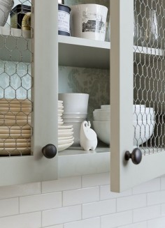 Kitchen with Chicken Wire Cabinet Doors. This kitchen boasts upper cabinets, with backs of shelves lined with gray damask wallpaper, accented with chicken wire doors. Jenny Wolf Interiors.
