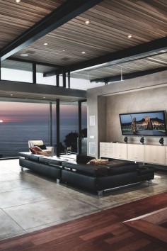 Living room: Grey marble/ wooden floors, ocean view, low lying black couch and flat screen TV