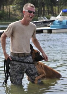 Military working dog Uutah clings to his handler, Staff Sgt. Justin Benfer, 92nd Security Forces Squadron, in the water. The MWDs perform training exercises in the water to keep up their confidence in different environments and stay mission-ready at all times.