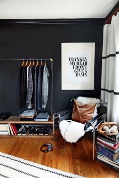 Minimal bedroom with a modern black chair, a lamb throw, and a rolling rack