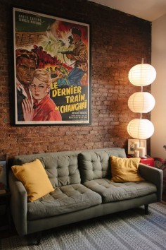 omg, these are a few of my favorite things, brick walls, dark couch, vintage poster and paper lamps!!!