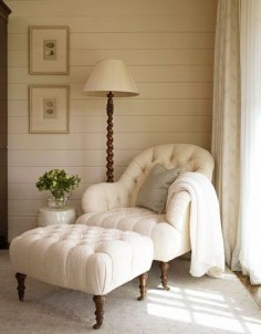 Peaceful reading nook with a tufted chair & ottoman, wood paneled walls, and spiral reading lamp