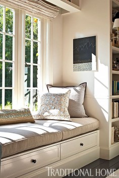 Sandwiched between floor-to-ceiling bookshelves, a sunny window seat provides a great place to read. - Photo: Michael Garland / Design: Chris Barrett