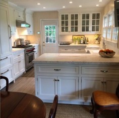 Small Southampton kitchen lives large:  Glass-fronts, large-scale hardware on paneled refrigerator, cabinetry also on dining side - Tom Samet