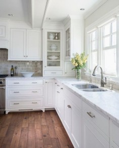 stunning light filled kitchen with inset white cabinets, medium toned, rustic hardwood floors, ceramic subway tile backsplash, marble counters