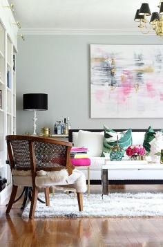 summer living room with pops of pink and green against a black white and gray backdrop. Chic accessories, palm pillows, abstract art, black shades.