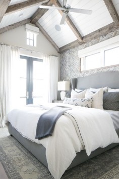 The gray, white, and navy tones in this master bedroom are breathtaking! We especially like the wood accent wall and exposed ceiling beams.