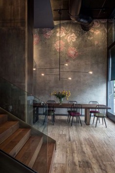 the high ceilings in concrete softened with a delicate pretty mural + unpolished wood flooring and stairs.