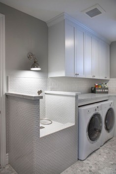 This stunning laundry room features white cabinets and a very practical pet shower and grooming station. Flooring is hex marble tiles.